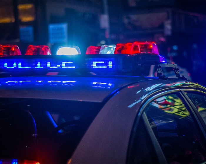 Police car with flashing lights at night, symbolizing the struggle after a party incident for a famous model. Police car with flashing lights at night, symbolizing the struggle after a party incident for a famous model.