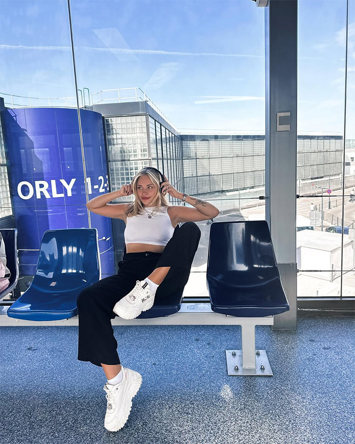 A young woman, who dreamed of becoming a famous model, sits casually on a bench in an airport lounge, wearing headphones. A young woman, who dreamed of becoming a famous model, sits casually on a bench in an airport lounge, wearing headphones.