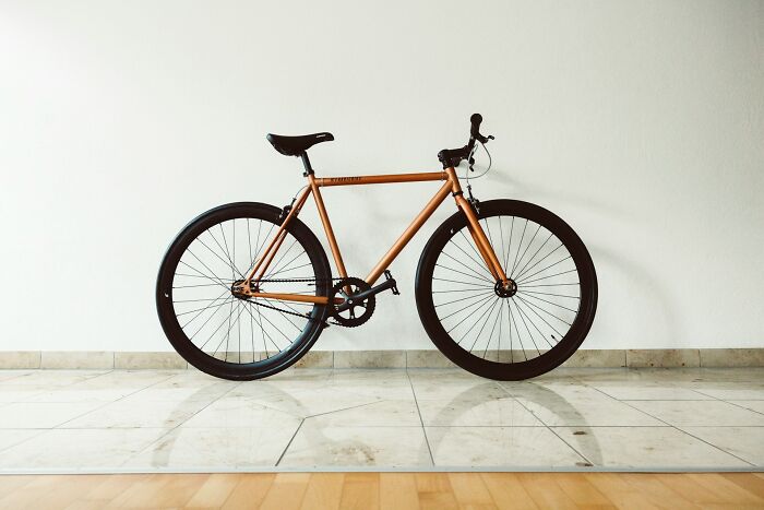A copper-colored fixed-gear bicycle against a white wall, representing a terrifying "we need to leave now" moment.