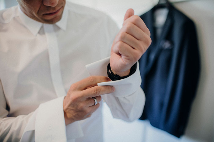 A groom adjusts his cufflink, unaware of potential wedding red flags in his marriage.