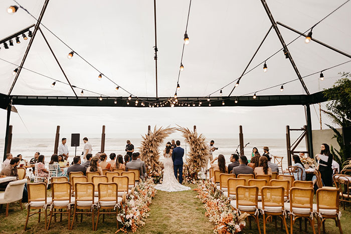 An outdoor wedding ceremony by the beach, with guests seated, hinting at the potential for wedding red flags.