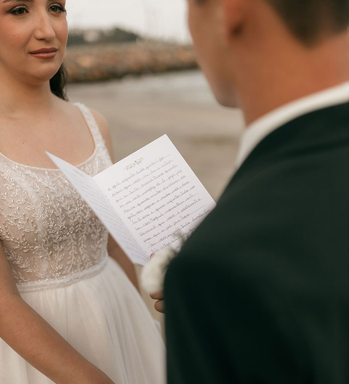 A bride looks at the groom, who is reading wedding vows. This highlights wedding red flags.