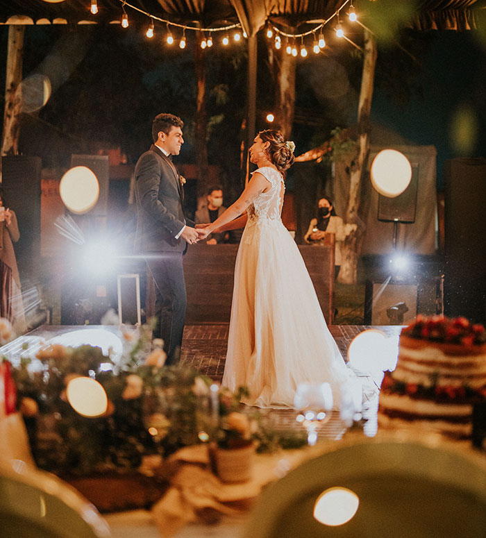 A newlywed couple slow dances under string lights at an outdoor wedding reception. This image is a stark contrast to the theme of wedding red flags, celebrating the happiness of marriage.