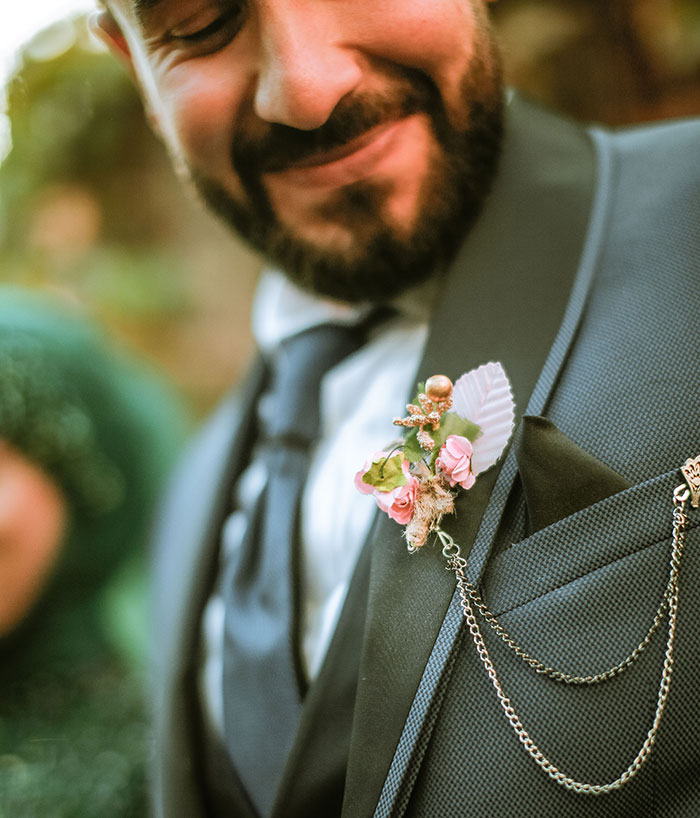 A close-up of a smiling groom's boutonnière, symbolizing potential wedding red flags.