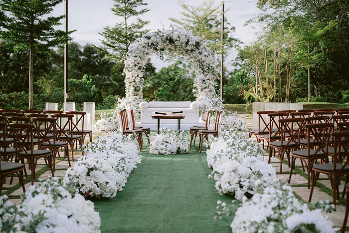 An elegant outdoor wedding setup with a floral arch and white flowers, hinting at marriage red flags.