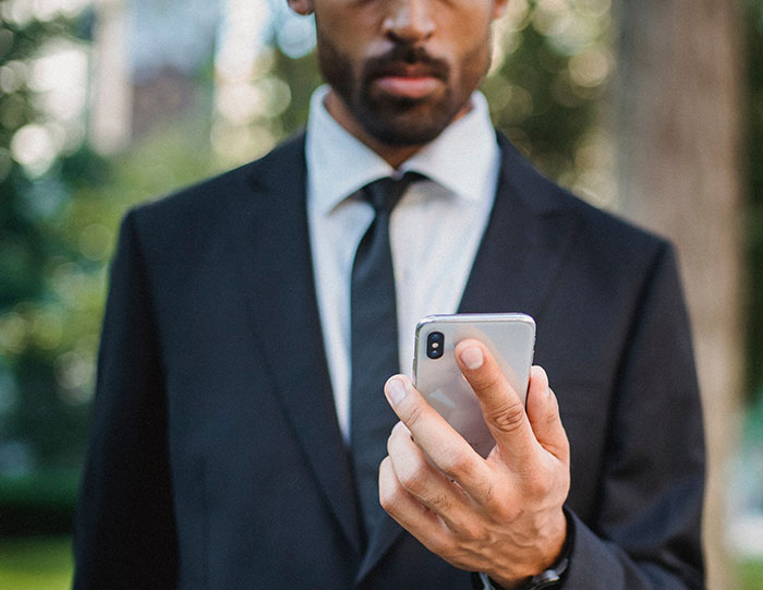 A man in a suit looking at his phone, illustrating a potential wedding red flag.