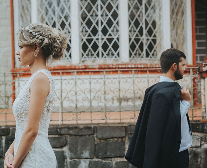 A bride and groom stand back-to-back, symbolizing the wedding red flags that can lead to a marriage ending.