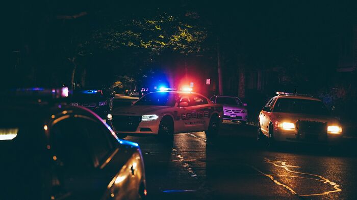 Terrifying scene with police cars at night, lights flashing, representing "we need to leave now" moments.