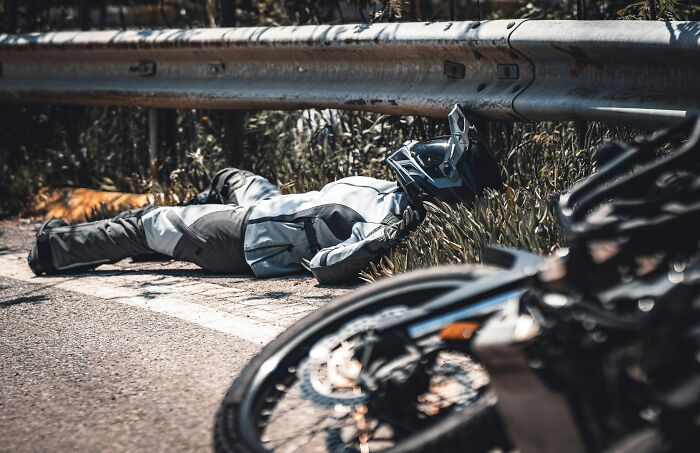 Motorcyclist lying injured next to a crashed motorcycle, highlighting instant justice.