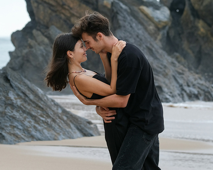 A couple embracing on a beach, facing each other, suggesting intimacy in the context of dating women with hip dips.