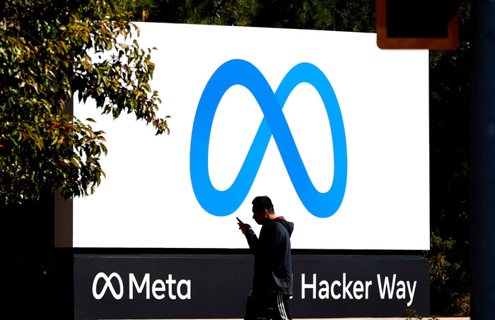 A man walks past the Meta logo sign on a sunny day, representing an ex-Meta worker and AI job replacement. A man walks past the Meta logo sign on a sunny day, representing an ex-Meta worker and AI job replacement.