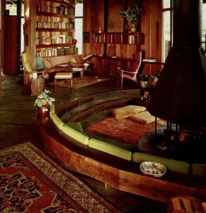 A cozy living room with a sunken circular fireplace and various seating areas, featuring iconic furniture and historic interiors.