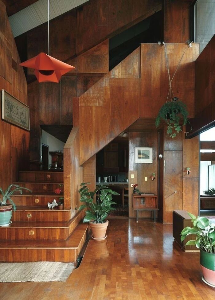 Remarkable Designs: A warmly lit interior with extensive wood paneling, a wooden staircase, and hanging plants, displaying remarkable design.