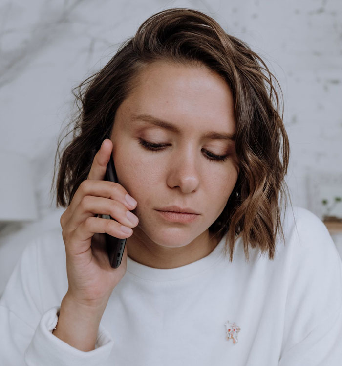 A woman looking distressed while talking on the phone, facing a mother-in-law issue.