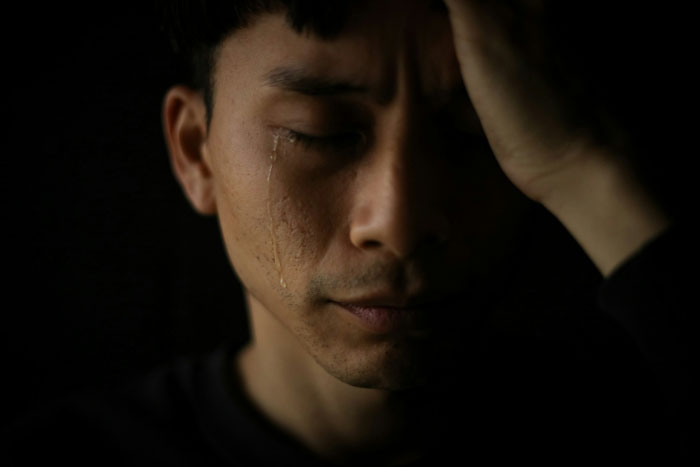 A man crying, deeply distressed, possibly due to a future mother-in-law calling his partner defective.