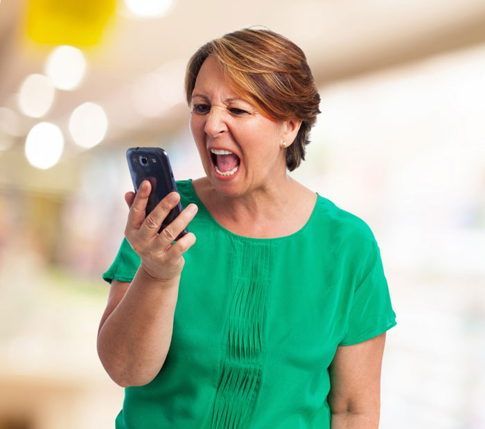 An angry woman yells at her phone, depicting the future mother-in-law's outrage about her son marrying.