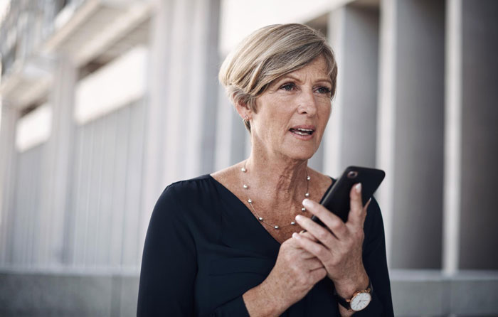 A concerned woman, possibly a toxic MIL, holding a phone, engaged in a conversation outdoors. A concerned woman, possibly a toxic MIL, holding a phone, engaged in a conversation outdoors.