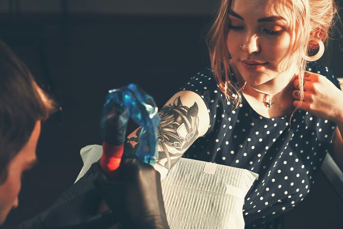 A young woman with a finished arm tattoo, showing the artistic skill of the tattoo artist and the client's satisfaction.
