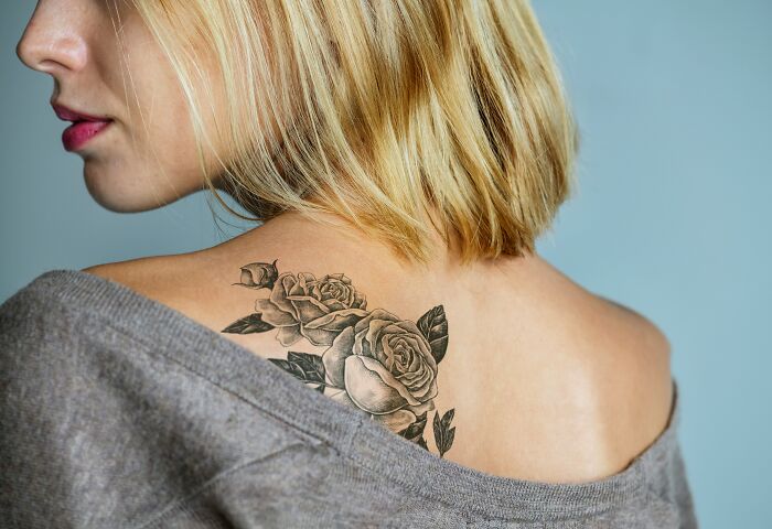 A woman with a beautiful rose tattoo on her shoulder, showcasing the artistic skill of tattoo artists.