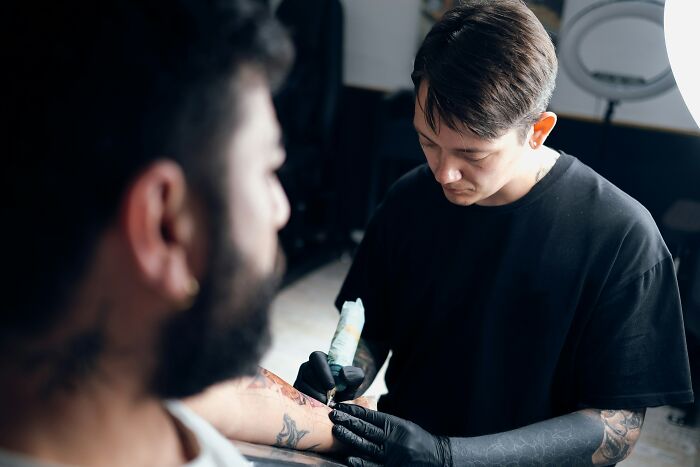 A tattoo artist applying a permanent tattoo on a client's arm, highlighting the detailed work of tattoo artists.