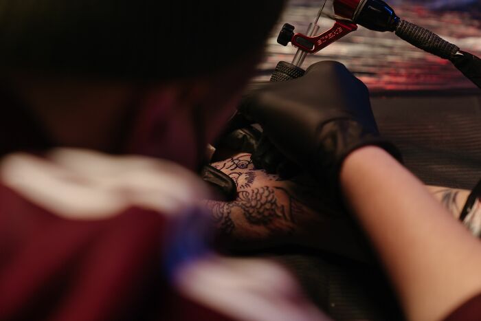 Close-up of a tattoo artist's gloved hands applying a detailed tattoo design, focusing on the precision of tattoo art.