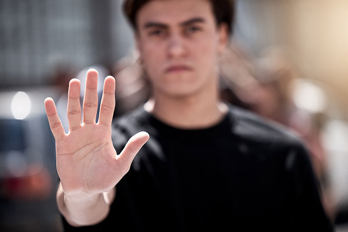 A teen holding up a hand in a stop gesture, representing refusal to donate a lung to his mom. A teen holding up a hand in a stop gesture, representing refusal to donate a lung to his mom.