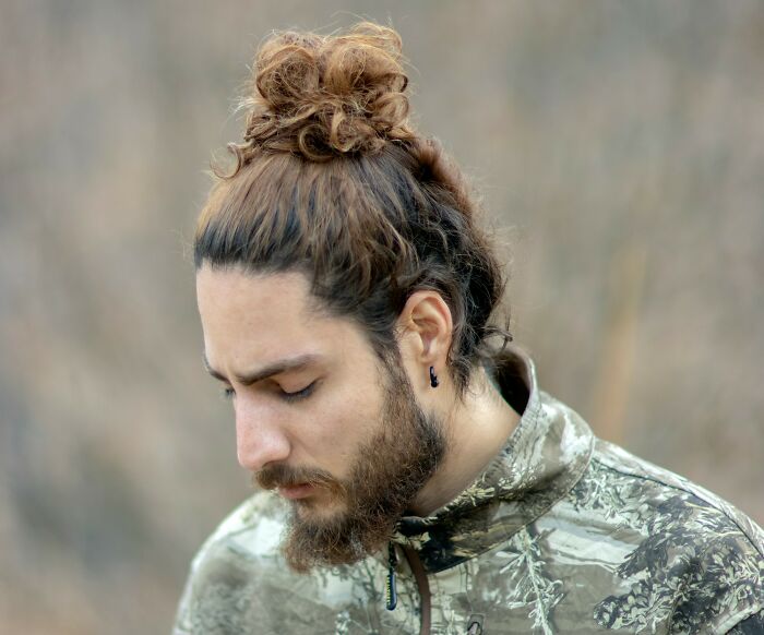 A man with a man bun and beard in a camouflage jacket, representing changing trends and swapped audiences.