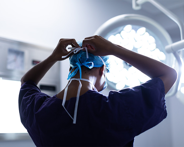 A doctor tying a surgical cap in an operating room, highlighting the risk of botched surgery. A doctor tying a surgical cap in an operating room, highlighting the risk of botched surgery.