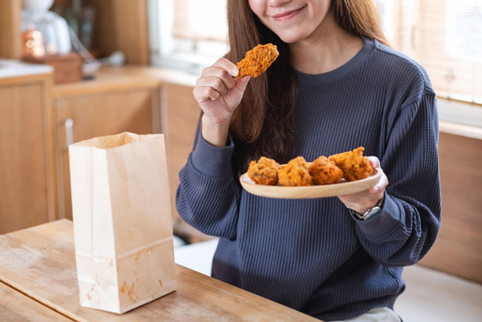 A woman happily eating fried chicken, representing the picky eater's preferred meal. A woman happily eating fried chicken, representing the picky eater's preferred meal.