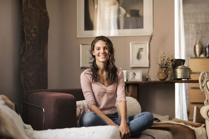 A smiling woman sitting on a couch, potentially a nanny, during a family vacation.