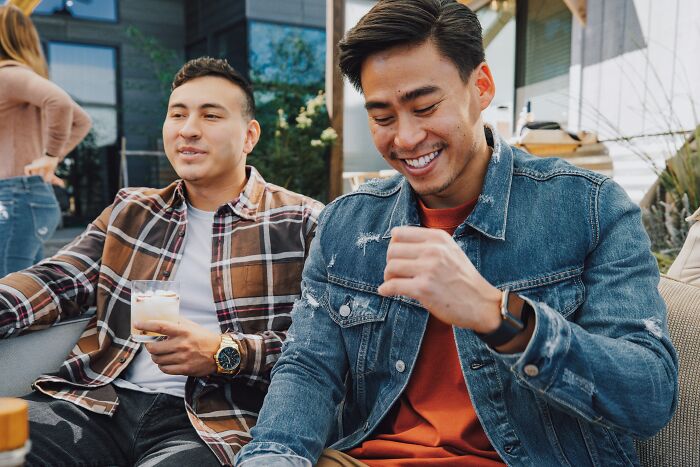 Two men enjoying a drink outdoors, a reminder to be mindful of pocket dial stories and lock your screen.