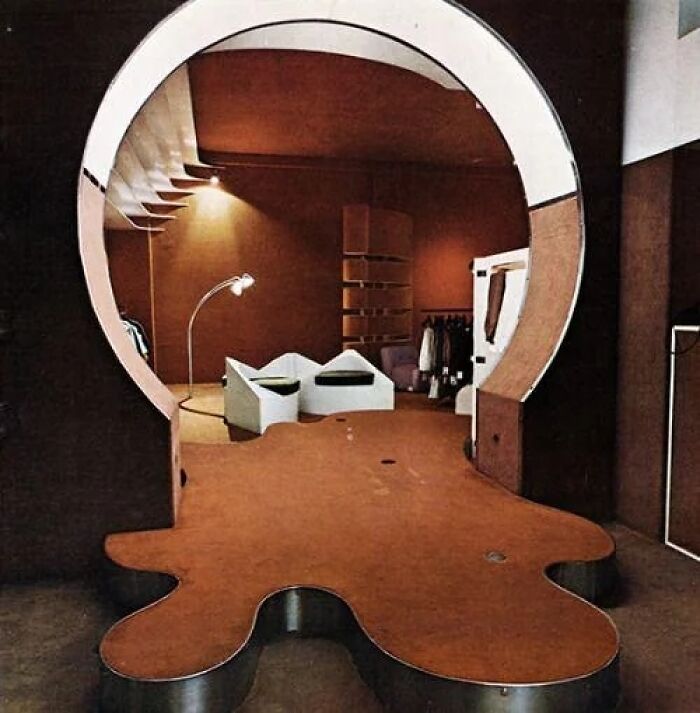 A unique Historic Interiors design with a large circular mirror reflecting an unusual room layout with white furniture and warm lighting.