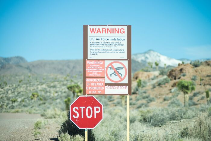 An Area 51 warning sign prohibiting entry and drones near an unsolved mystery site in a desert landscape.
