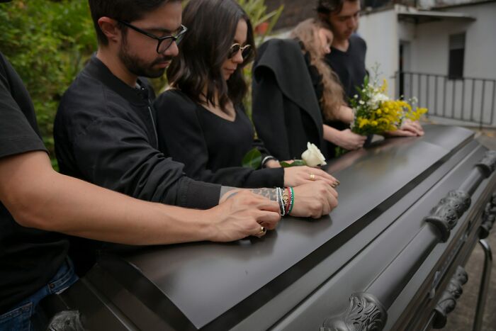 People standing around a casket, possibly representing the profound culture shocks experienced by international partners during loss.
