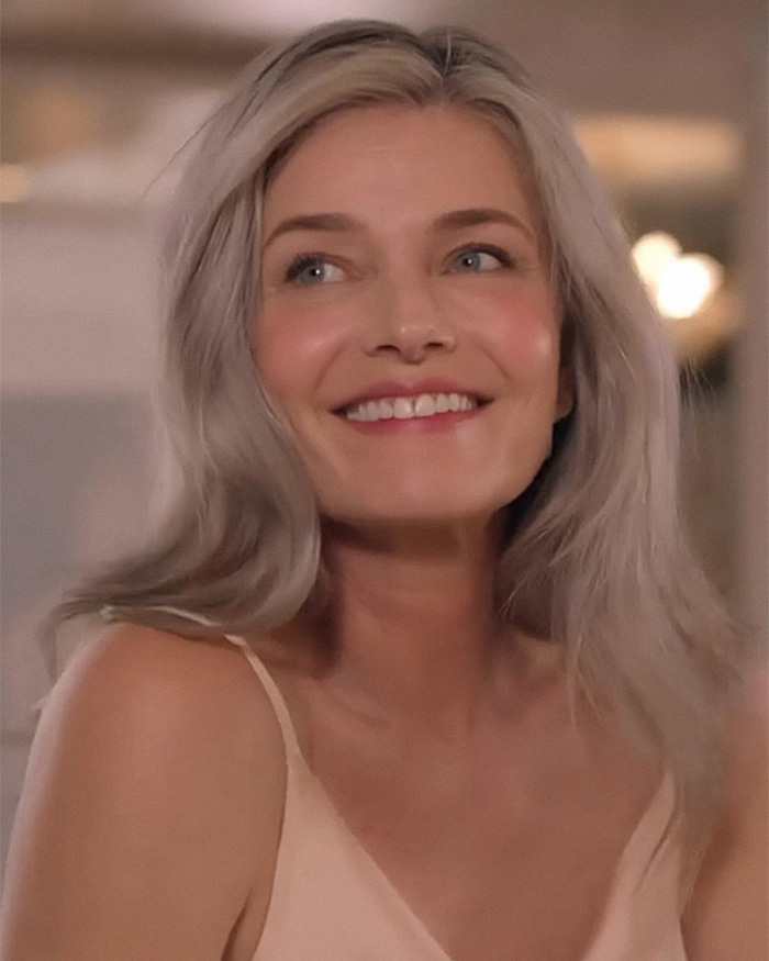 A close-up of a model, smiling and looking upward, showcasing her aged beauty and captivating presence.