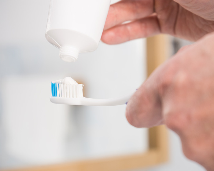 Hands squeezing toothpaste onto a toothbrush, a common method for a white smile. Hands squeezing toothpaste onto a toothbrush, a common method for a white smile.