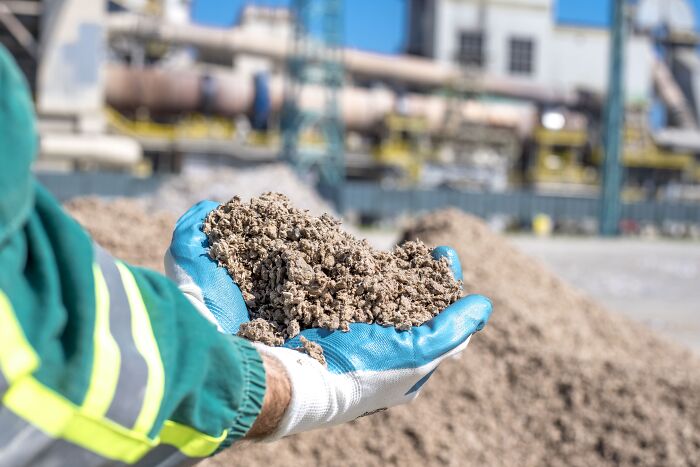 Gloved hand holding a pile of processed sand, highlighting sand and unpopular industries that make millions.