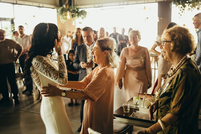 A bride embracing an older woman at a wedding reception, representing MILs stories.