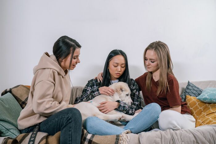 Three friends supporting each other and a dog, highlighting psychological red flags in relationships.