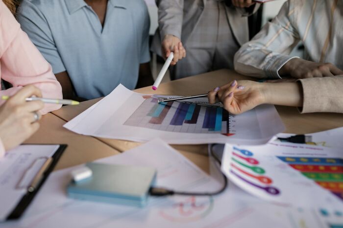 A group of people reviewing charts and graphs on a table, discussing behind the scenes secrets companies don't want you to know.