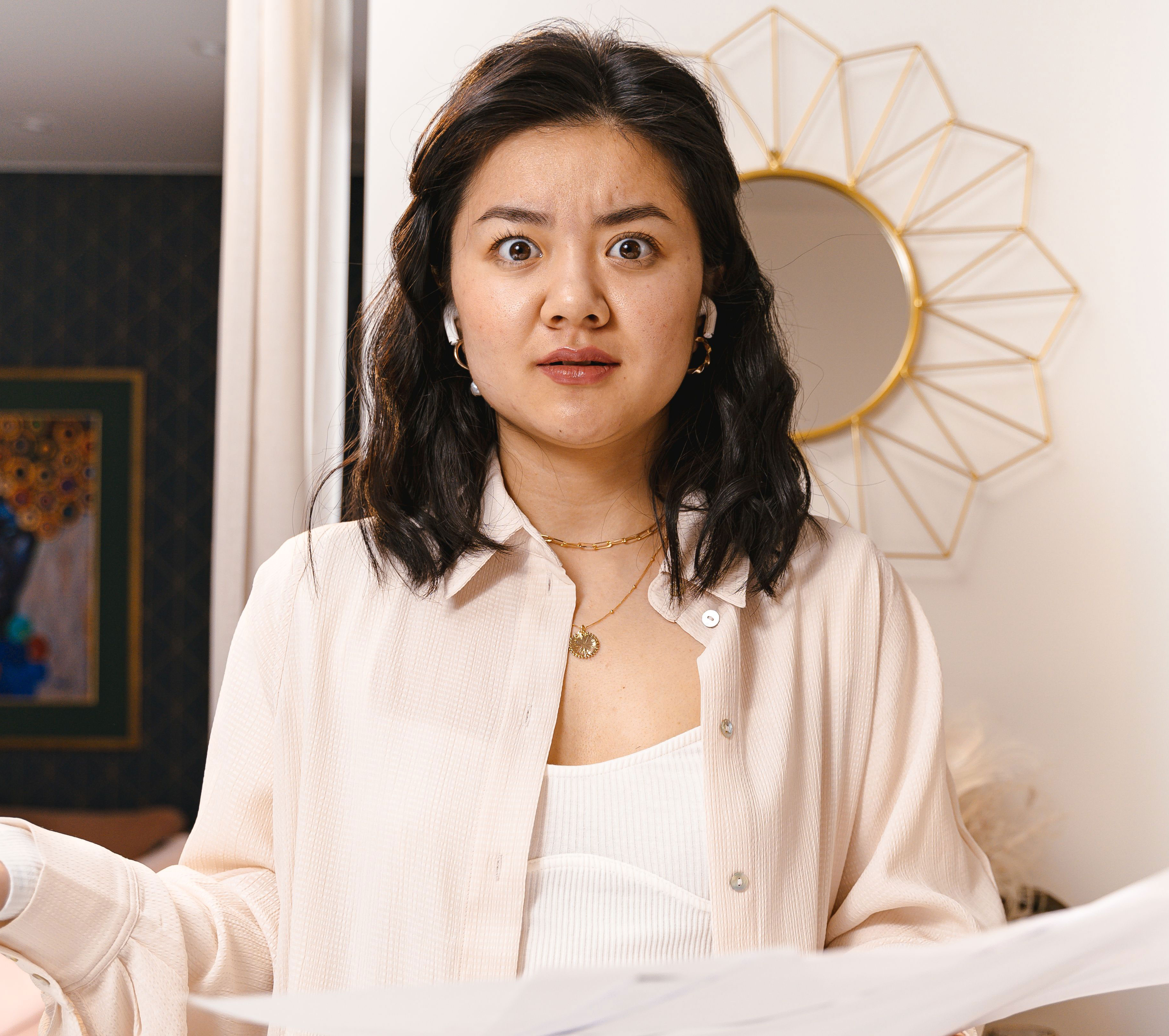 A teenage girl with a shocked expression, wearing a light shirt and wireless earbuds, representing sexist remarks. A teenage girl with a shocked expression, wearing a light shirt and wireless earbuds, representing sexist remarks.