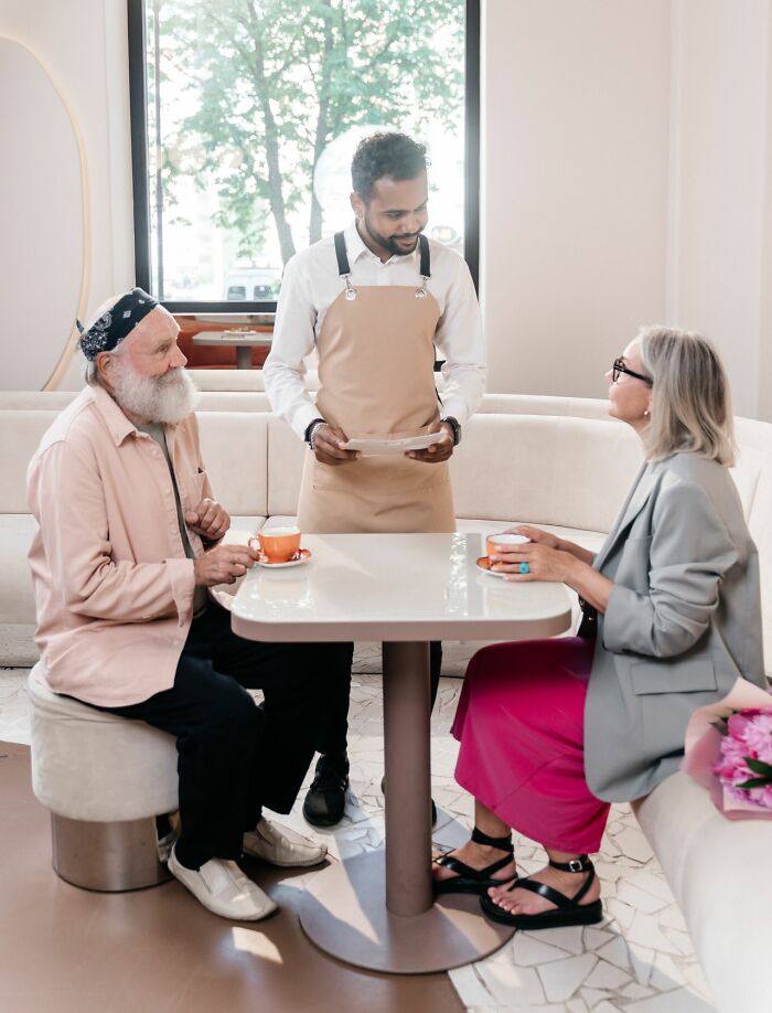 A waiter serving a couple in a cafe, illustrating American habits of dining out.