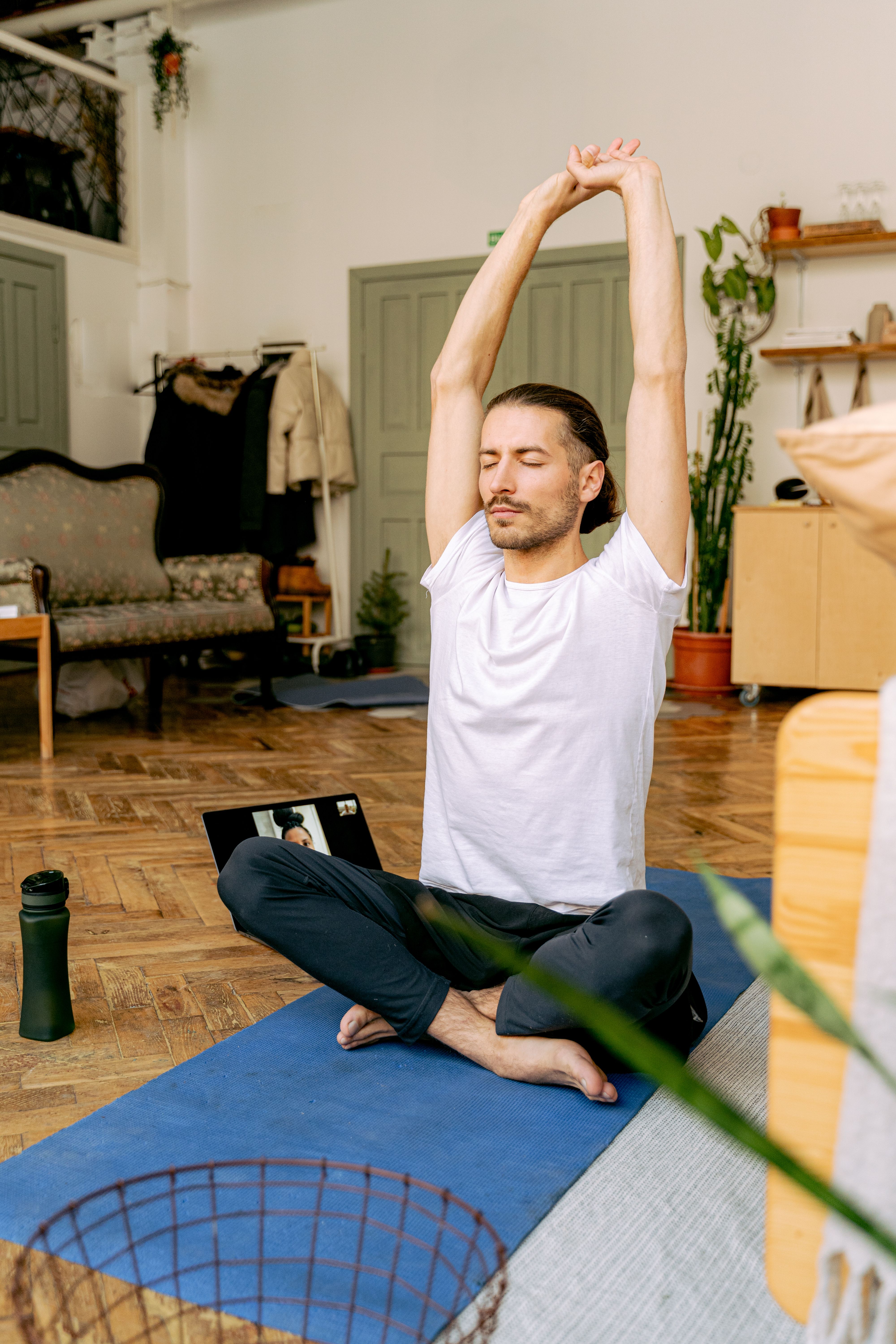 A man meditating with arms raised, following an online class, illustrating a simple trick for a changed life.