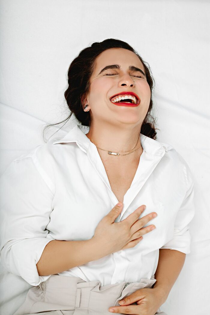 A woman laughing joyfully, potentially having heard surprising secrets people weren’t supposed to know.