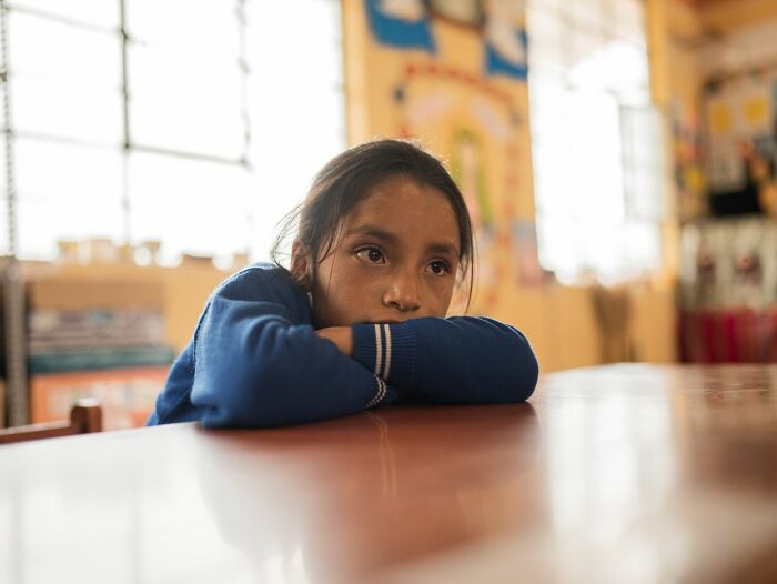 A young girl looking deeply evil and away from creeps, resting her head on a table, showcasing people's instincts.