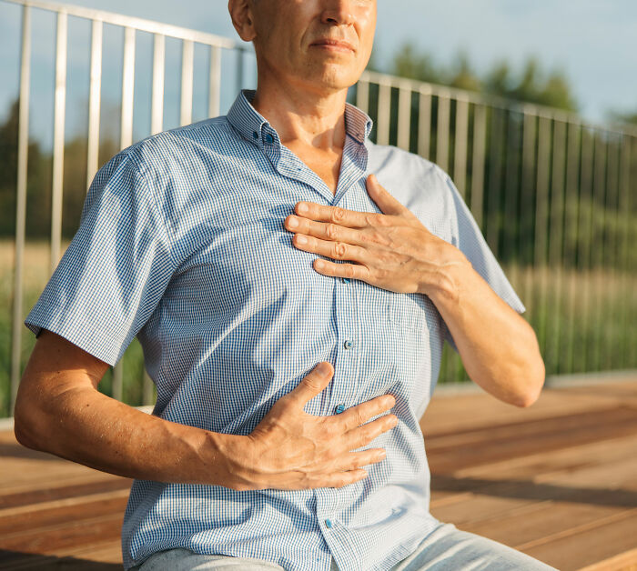 A man holding his chest, indicating a potential warning sign of pneumonia. A man holding his chest, indicating a potential warning sign of pneumonia.