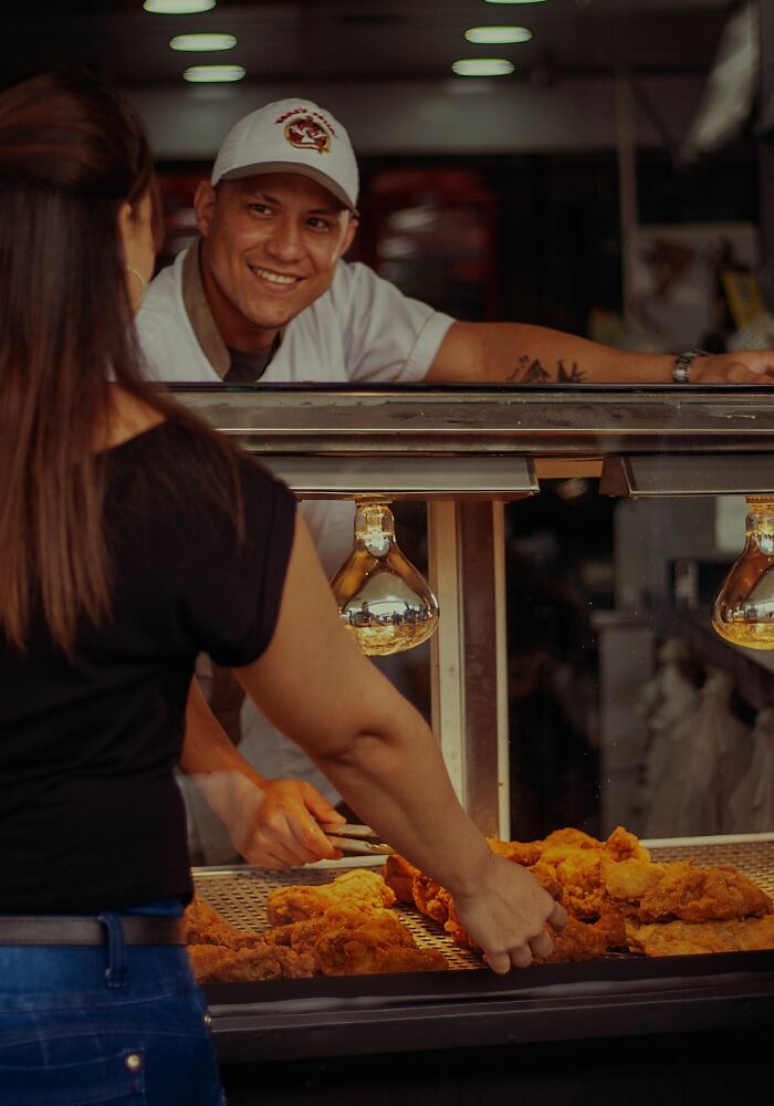 A vendor serving fried chicken to a customer, showcasing American habits and food culture.