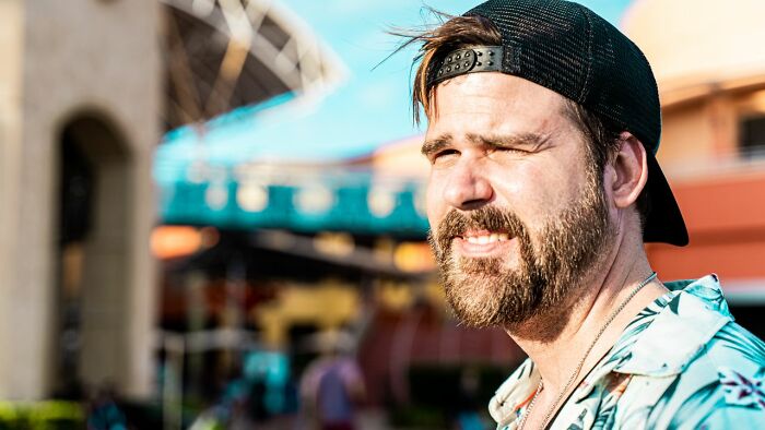 A man with a beard and a cap, looking off to the side, potentially experiencing public horror stories.