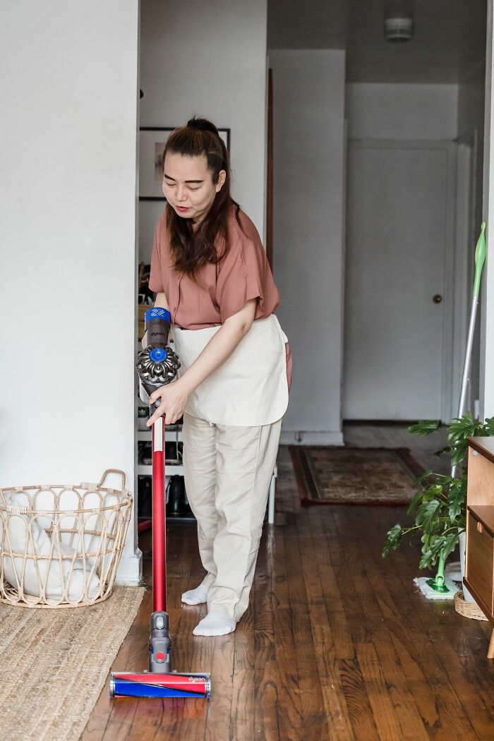 A woman vacuuming her floor, potentially a small cheating red flag if chores are suddenly out of routine.