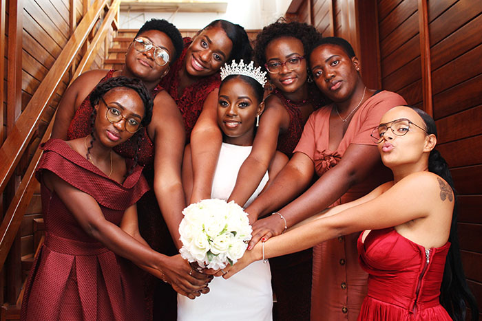 A happy bride holding a white bouquet, surrounded by bridesmaids in maroon dresses, showing a beautiful wedding. A happy bride holding a white bouquet, surrounded by bridesmaids in maroon dresses, showing a beautiful wedding.